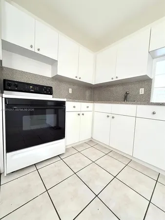 a kitchen with granite countertop a stove top oven and cabinets