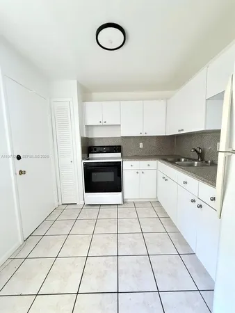a kitchen with granite countertop a stove a sink and a refrigerator