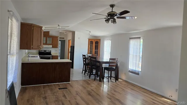 a kitchen with stainless steel appliances kitchen island granite countertop a refrigerator a stove a microwave oven a dining table and chairs with wooden floor