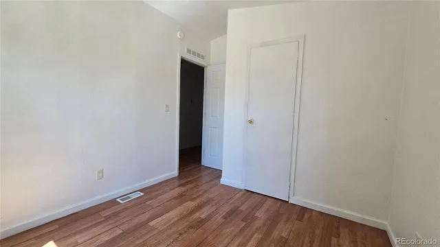 a view of an empty room with closet and wooden floor
