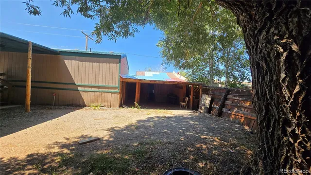 a view of backyard with wooden fence and a large tree