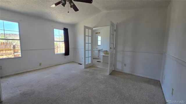 an empty room with chandelier fan and windows