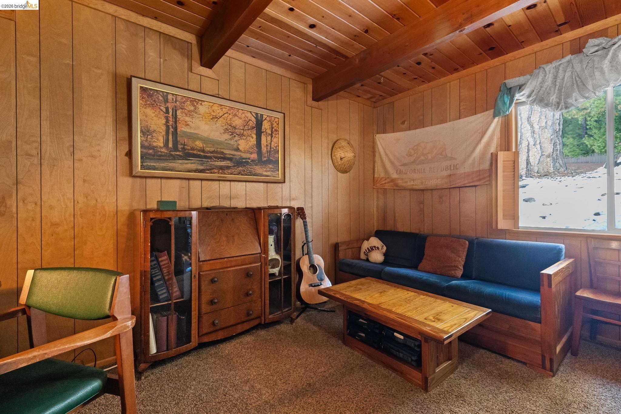 26039 Long Barn Road Long Barn, CA 95335 - Photo 16 of 27 Living area with wood walls, carpet flooring, and a wooden ceiling with exposed beams