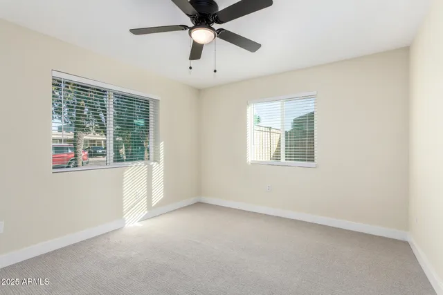 an empty room with a window and a ceiling fan