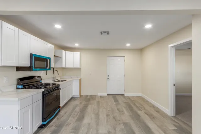 a kitchen with granite countertop a stove top oven a sink dishwasher and a refrigerator with wooden floor