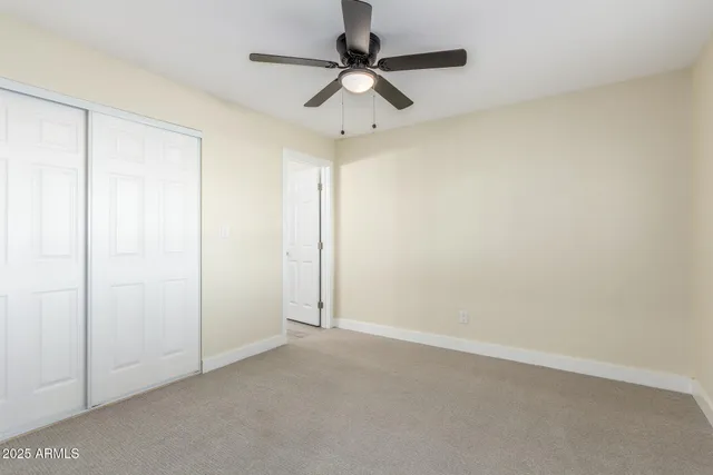 an empty room with a ceiling fan and carpet