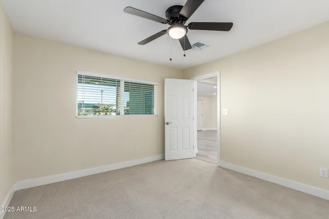 an empty room with a ceiling fan and a window