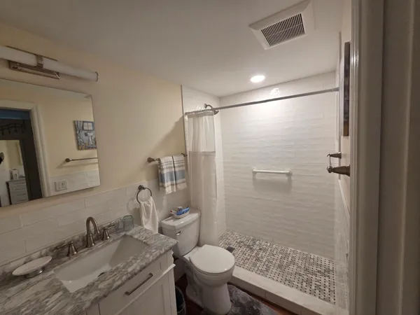 a bathroom with a granite countertop sink toilet and shower