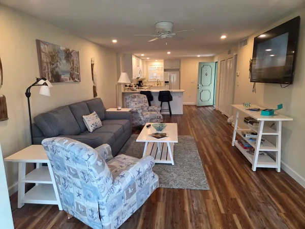 a living room with furniture a flat screen tv and kitchen view