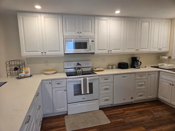 a kitchen with granite countertop white cabinets and white appliances