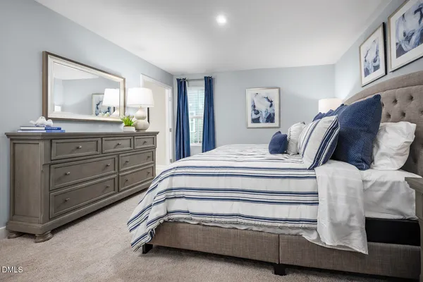 a spacious bedroom with a bed and a lamp on dresser