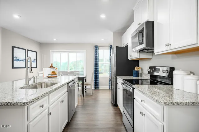a kitchen with granite countertop a refrigerator and a stove top oven