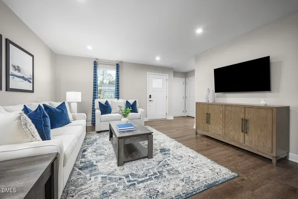 a living room with furniture a flat screen tv and a window