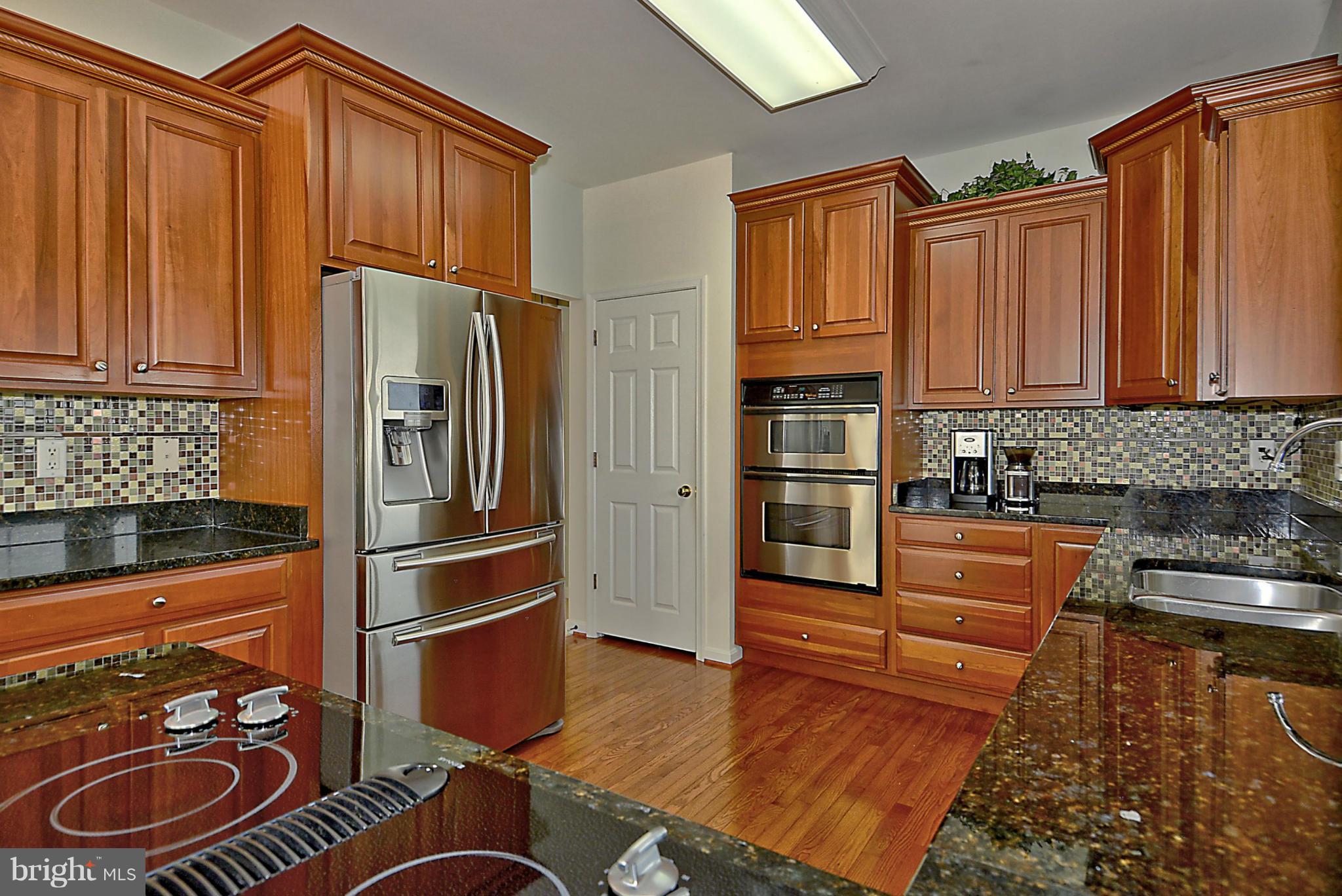 1001 Long Point Road Grasonville, MD 21638 - Photo 8 of 29 a kitchen with stainless steel appliances granite countertop a refrigerator a stove and a sink with wooden cabinets
