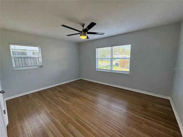 a view of empty room with wooden floor and fan