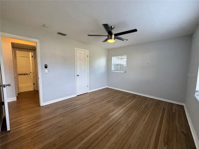 a view of empty room with wooden floor and fan