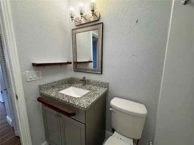 a bathroom with a granite countertop sink a toilet and mirror