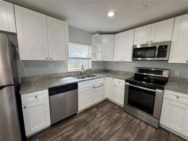 a kitchen with stainless steel appliances granite countertop a stove a sink and a microwave