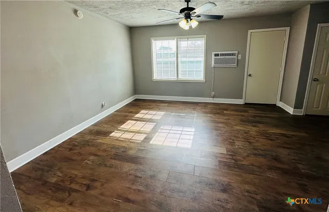 an empty room with wooden floor fan and windows