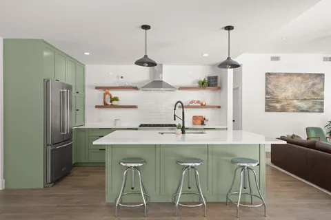 a kitchen with kitchen island stainless steel appliances a table chairs refrigerator and sink