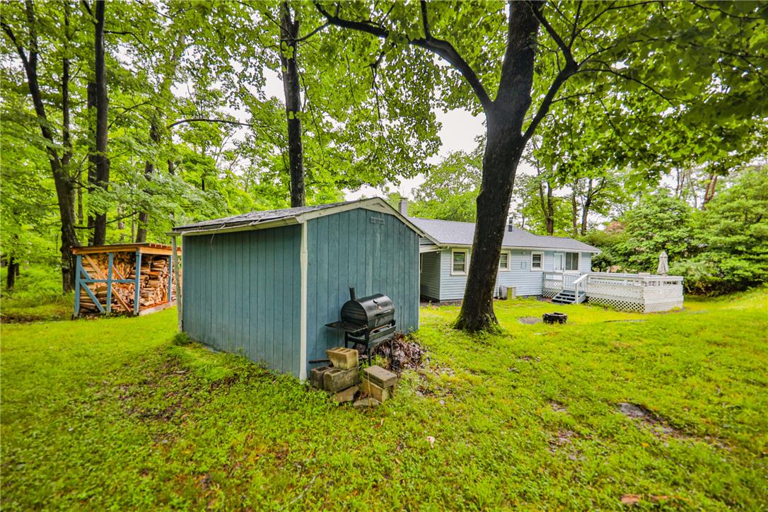 5599 Minks Pond Road Bushkill, PA 18324 - Photo 52 of 64 A verdant backyard with a wooden deck, ready for outdoor enjoyment and relaxation.
