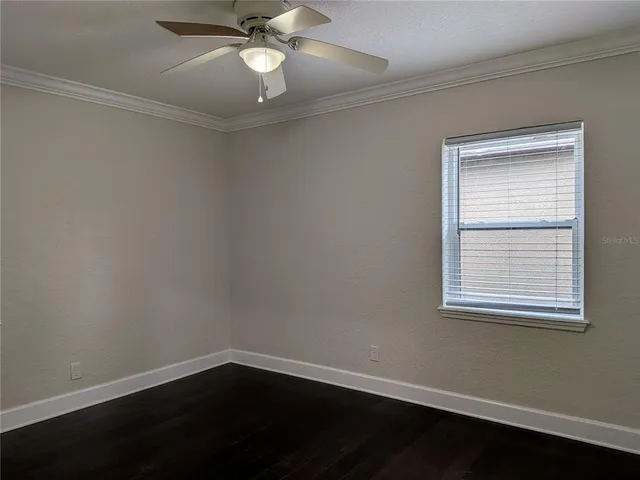an empty room with wooden floor closet and windows