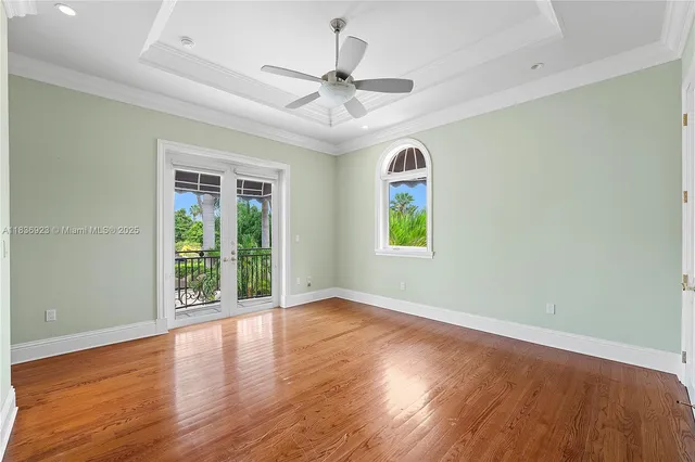 an empty room with wooden floor chandelier fan and windows