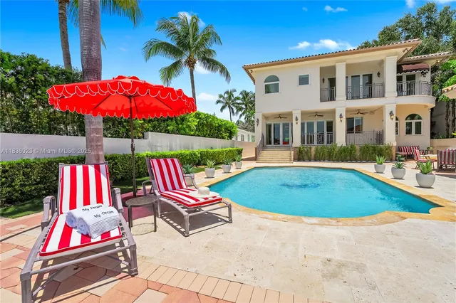 a view of swimming pool with red chairs in front of house