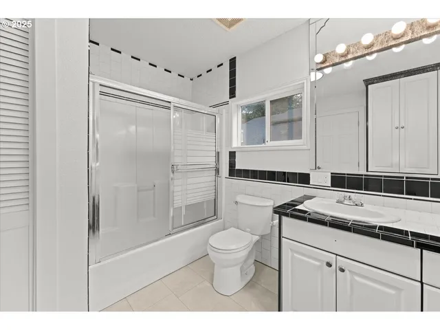 a bathroom with a granite countertop sink a toilet a mirror and shower