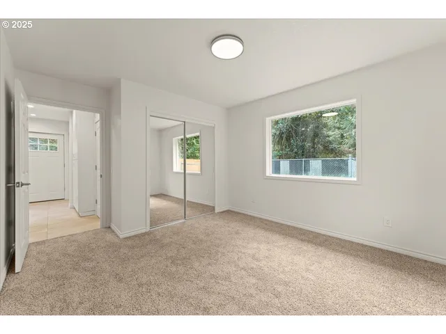 a view of an empty room with window and closet area