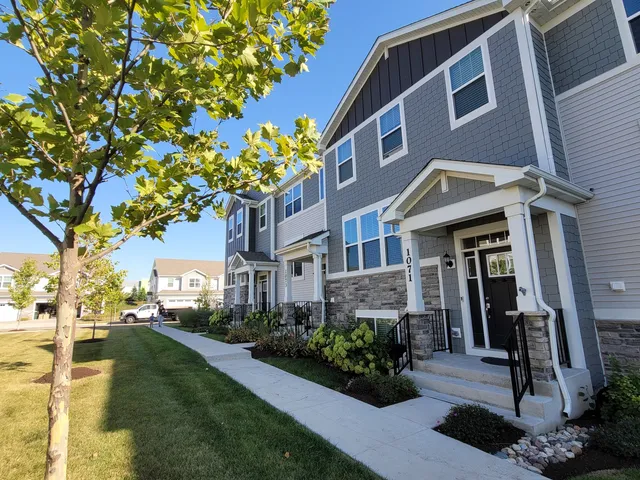 a front view of a multi story residential apartment building with yard and car parked