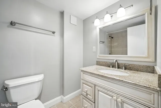 a bathroom with a granite countertop sink mirror vanity and toilet