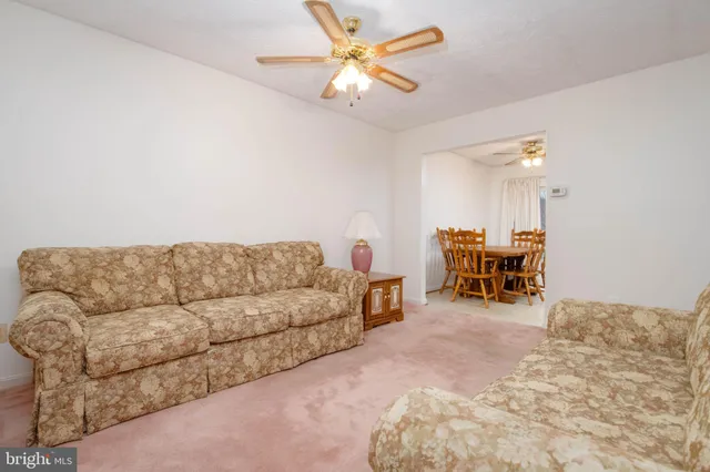 a living room with furniture and a dining table with chandelier