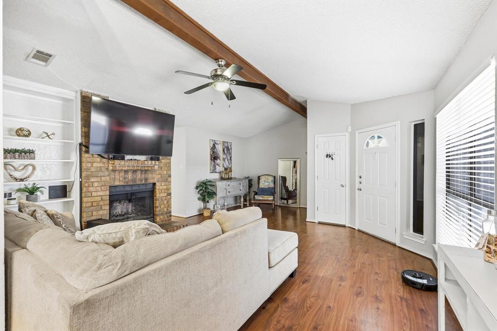 1312 Hackamore Street Mesquite, TX 75149 - Photo 5 of 23 Living room with ceiling fan, dark wood-style floors, a fireplace, built in features, and beamed ceiling