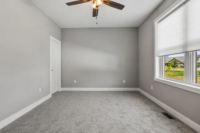 an empty room with windows and chandelier fan