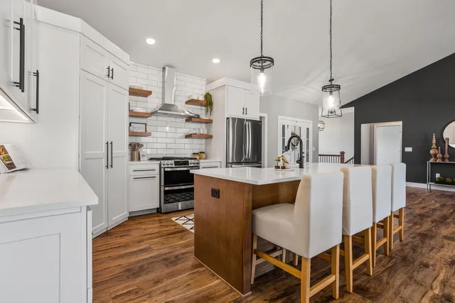 a kitchen with stainless steel appliances kitchen island granite countertop a table chairs stove and refrigerator