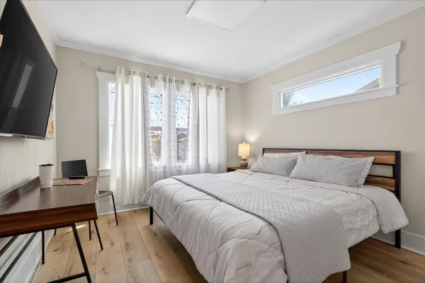 a bedroom with a bed a flat screen tv and a large window