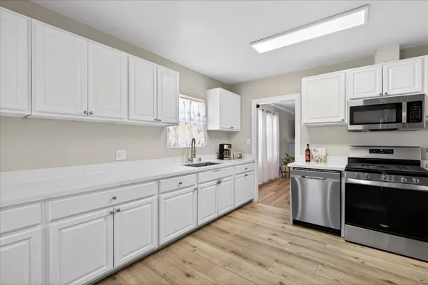 a kitchen with granite countertop white cabinets and stainless steel appliances