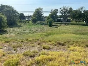 a view of a green field with wooden fence