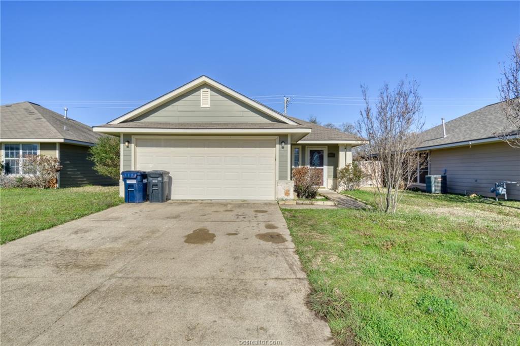 Single story home featuring a garage, driveway, a