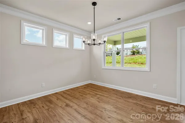 a view of a room with wooden floor chandelier and windows
