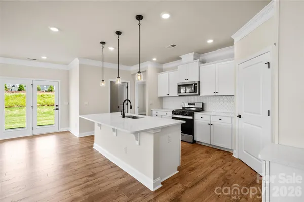 a large kitchen with stainless steel appliances kitchen island granite countertop a stove a sink a refrigerator and a wooden cabinets with wooden floor