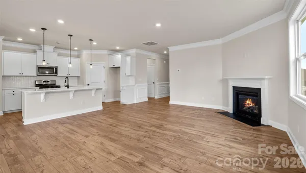 a view of kitchen with kitchen island a sink wooden floor and a fireplace