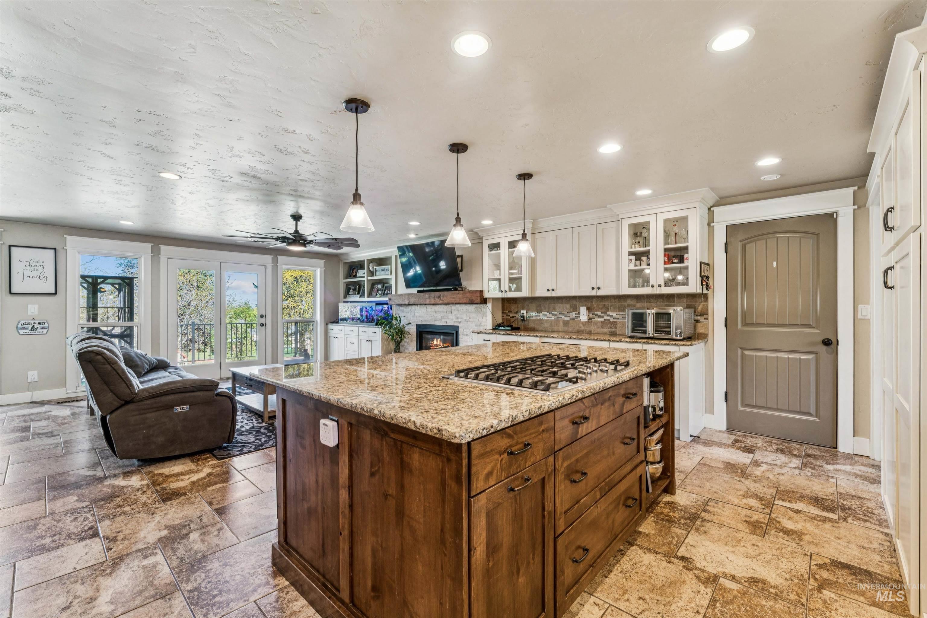 1050 West South Slope Road Emmett, ID 83617 - Photo 49 of 49 Kitchen featuring a center island, open floor plan, hanging light fixtures, light stone countertops, and a stone fireplace