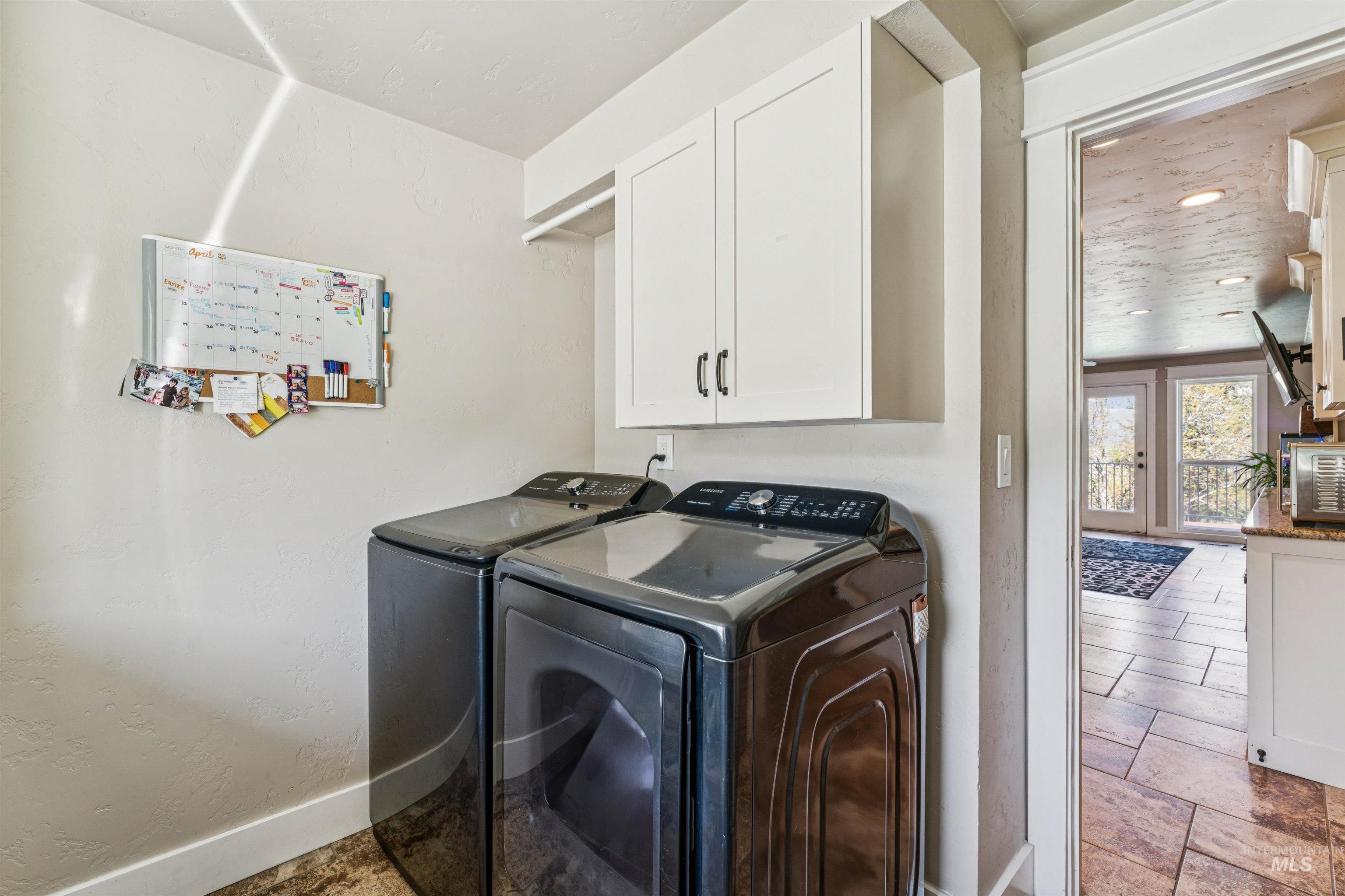 1050 West South Slope Road Emmett, ID 83617 - Photo 15 of 49 Laundry room with cabinet space, stone tile floors, and washing machine and clothes dryer