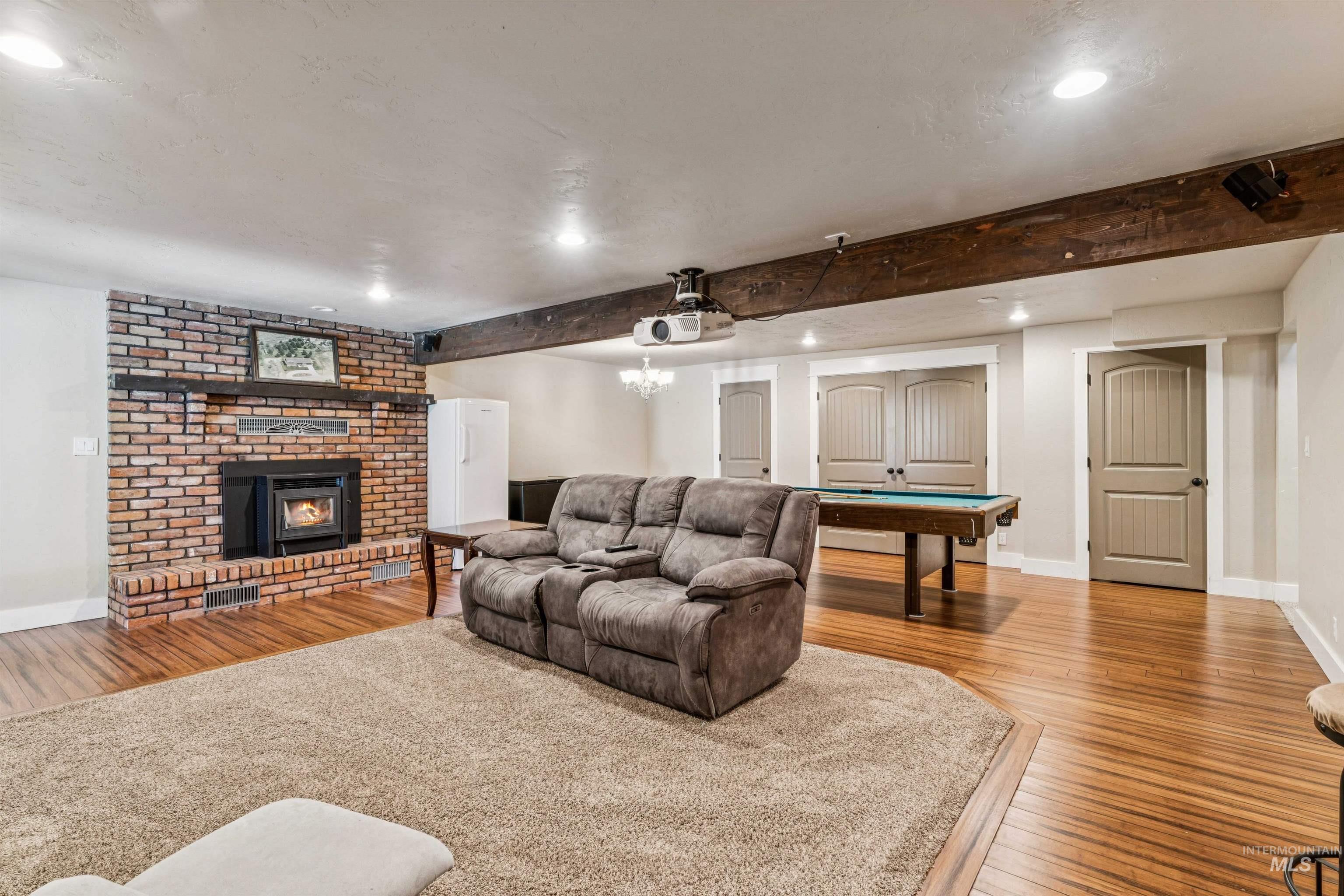1050 West South Slope Road Emmett, ID 83617 - Photo 28 of 49 Living area with light wood-style flooring, beam ceiling, billiards table, a fireplace, and hanging lights