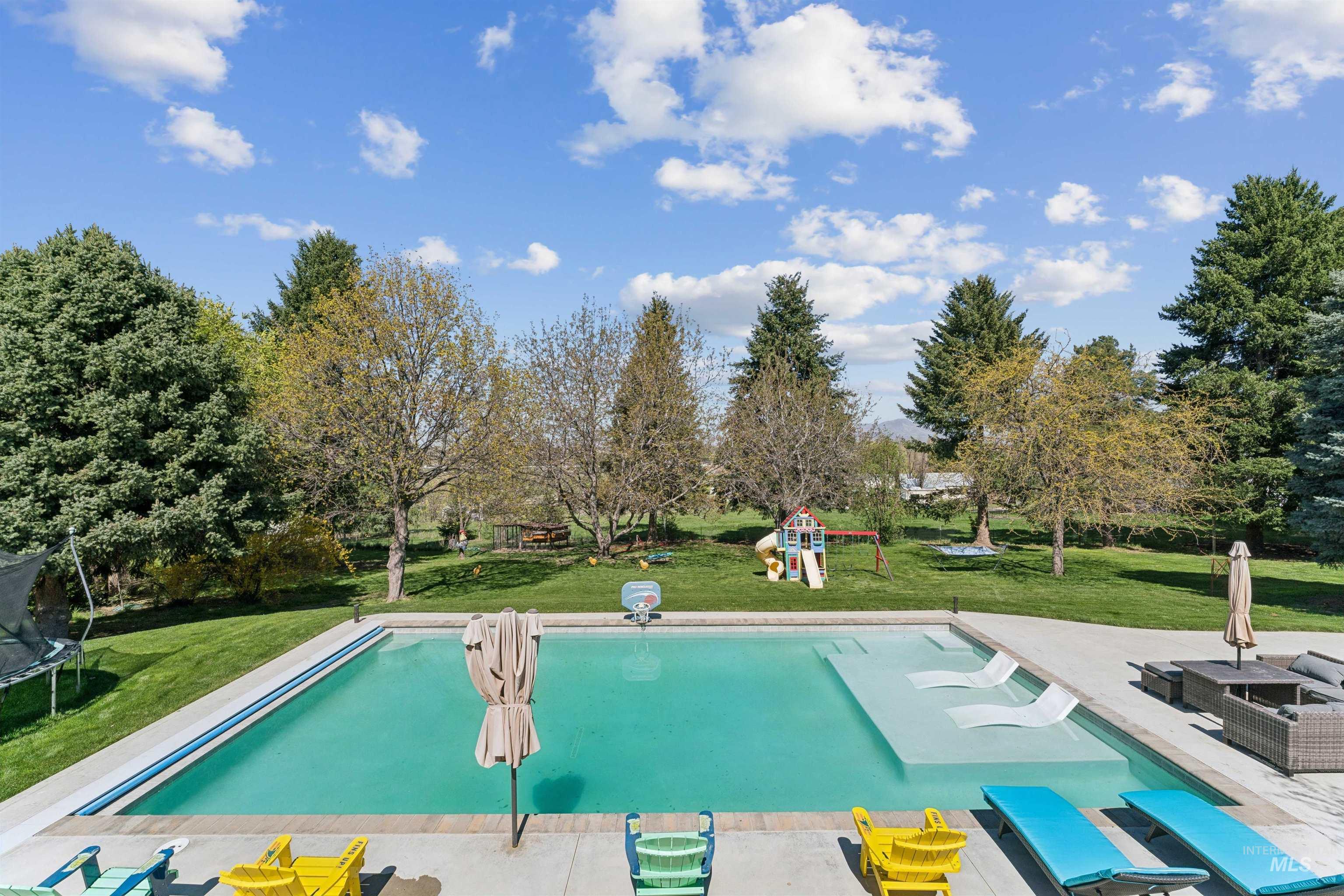 1050 West South Slope Road Emmett, ID 83617 - Photo 36 of 49 Outdoor pool featuring a lawn, a trampoline, a patio area, and view of wooded area