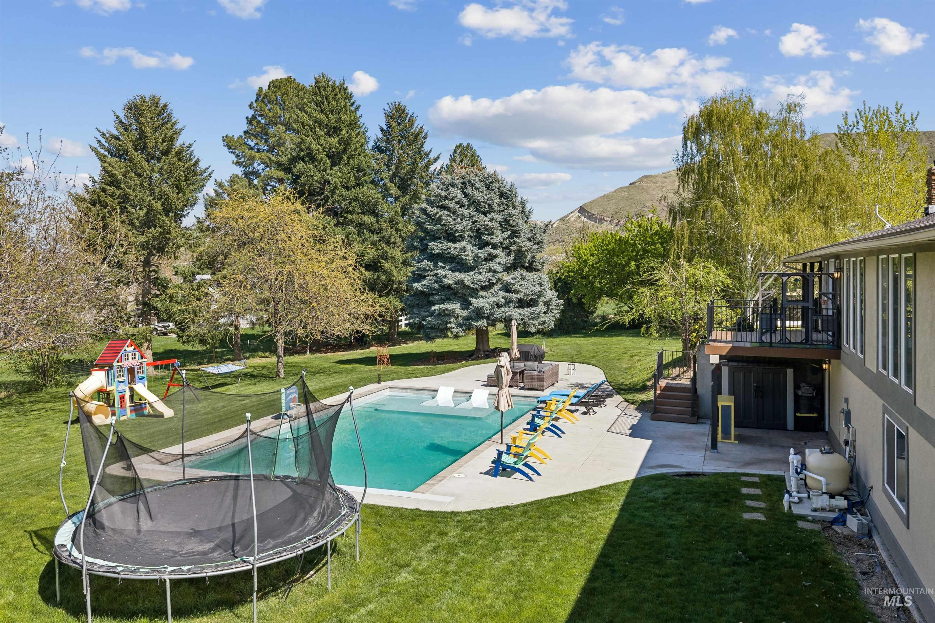 1050 West South Slope Road Emmett, ID 83617 - Photo 37 of 49 Swimming pool featuring a patio area, a yard, a trampoline, a playground, and a deck with mountain view
