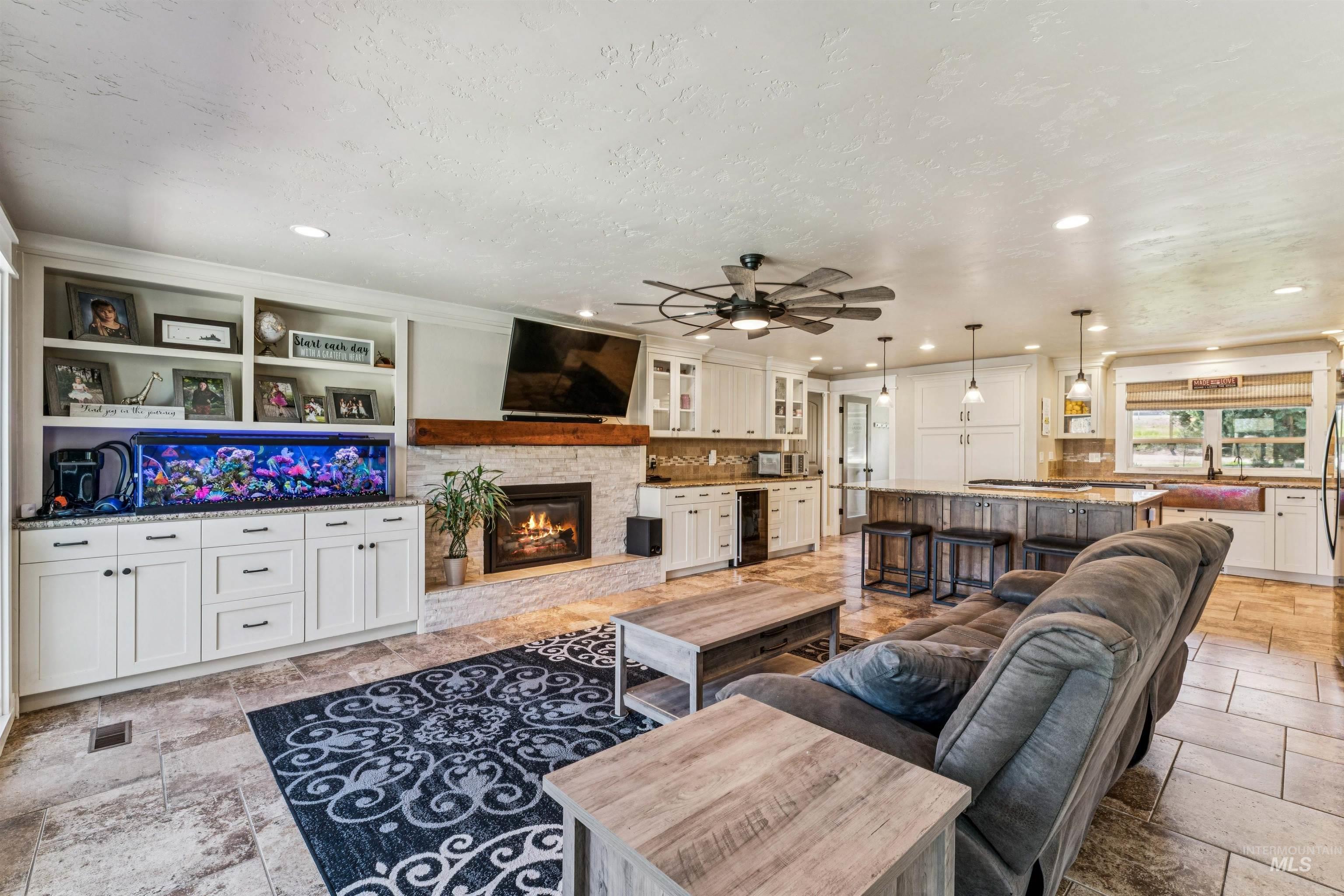 1050 West South Slope Road Emmett, ID 83617 - Photo 7 of 49 Living area featuring stone tile floors, a stone fireplace, ceiling fan, recessed lighting, and beverage cooler