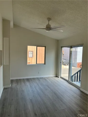 an empty room with wooden floor fan and windows